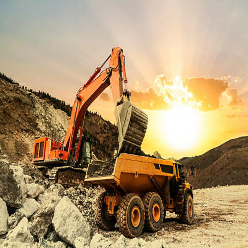 Excavator loading dumper truck on mining site at sunset